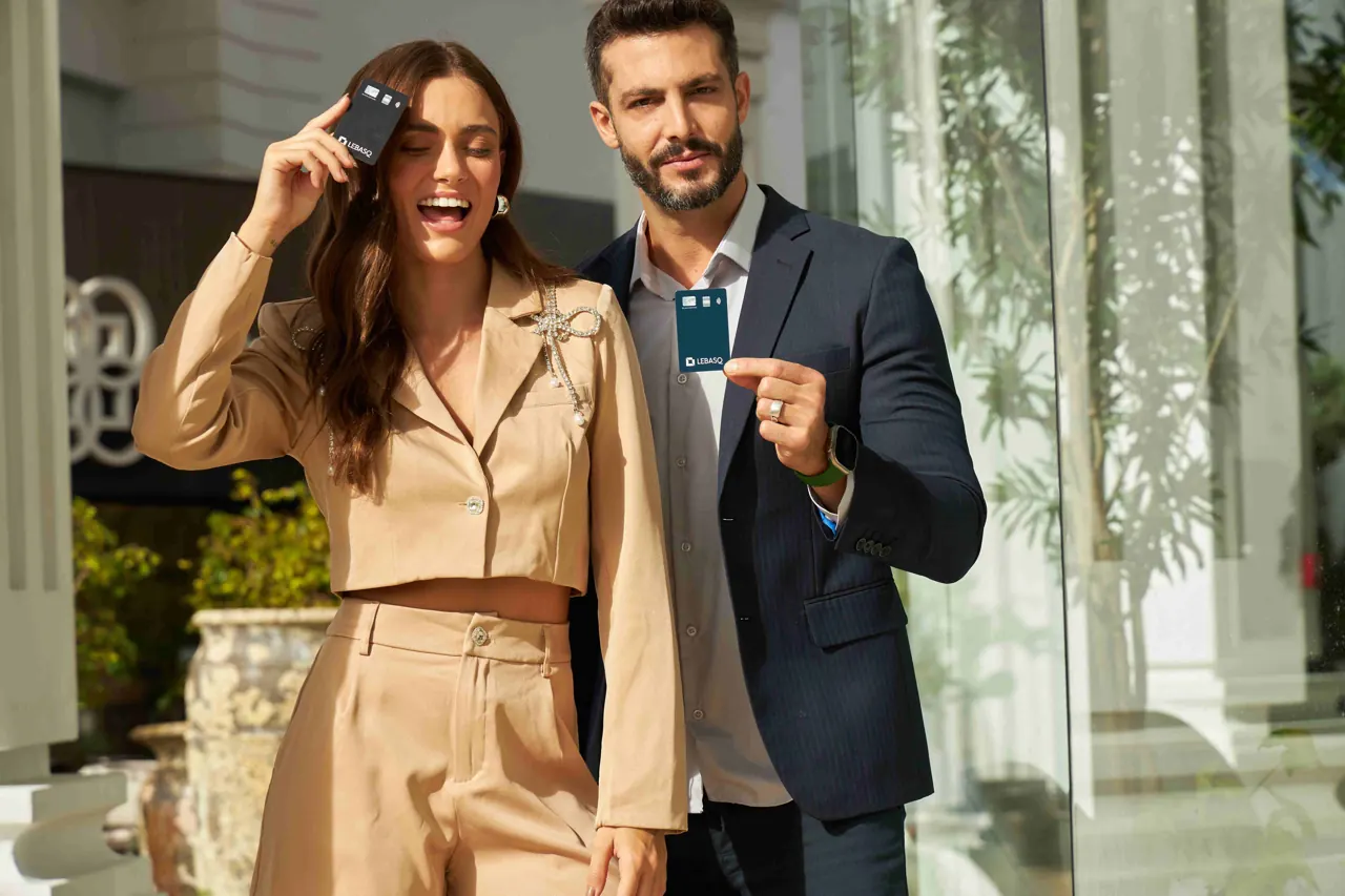 Casal sorrindo segurando o cartão LEBASQ